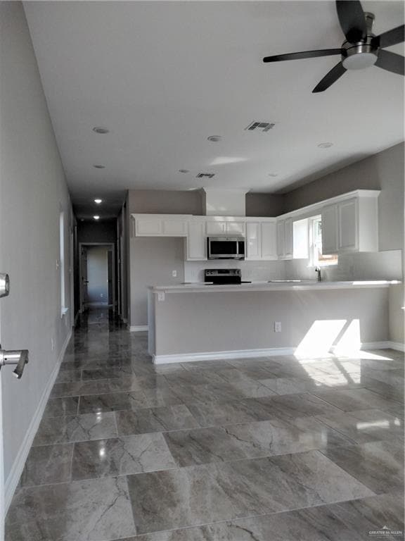 Kitchen featuring white cabinetry, baseboards, marble finish floor, visible vents, and a ceiling fan