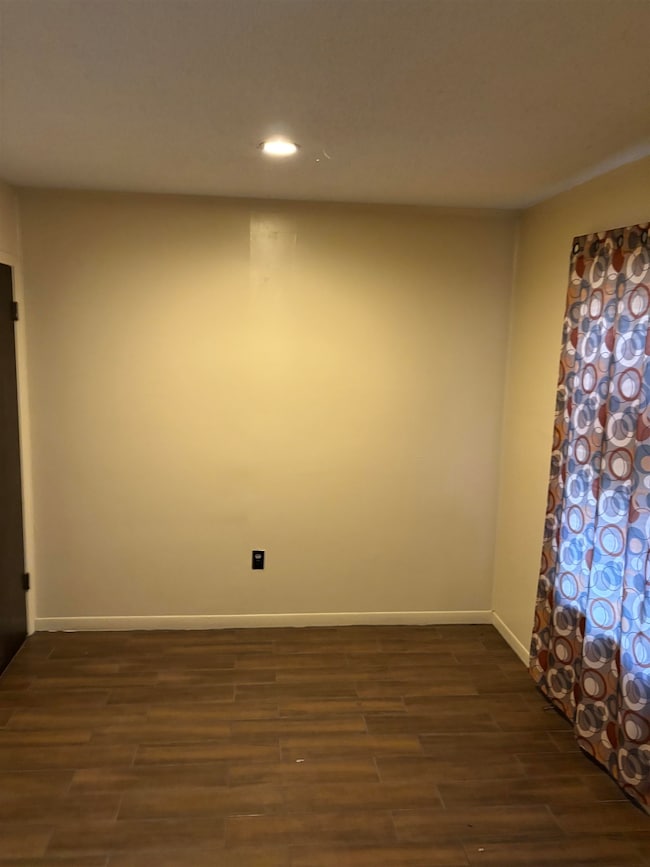 Empty room featuring dark wood-style floors, reces