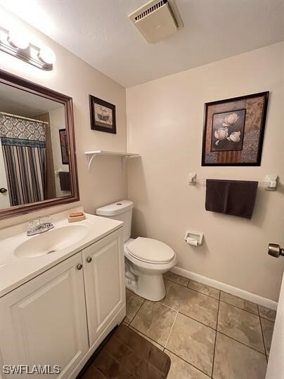 Bathroom featuring vanity, baseboards, toilet, til