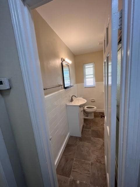 Bathroom with vanity, toilet, and tile walls