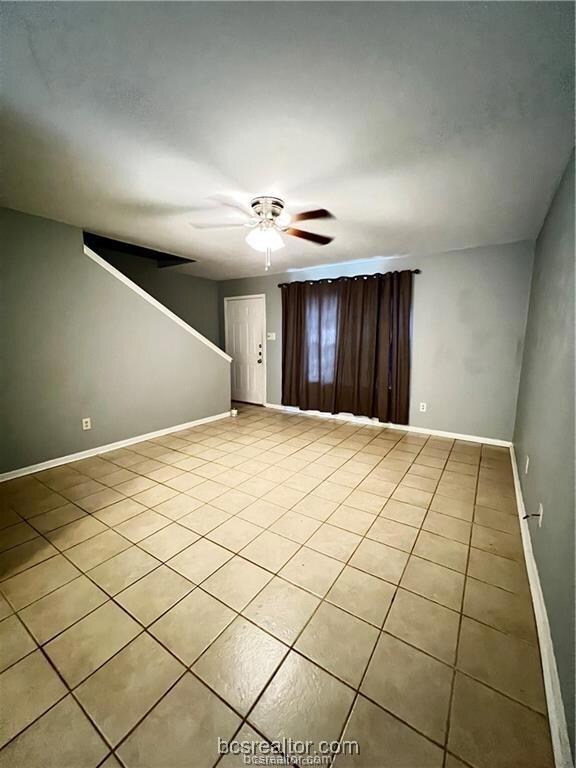 Empty room featuring ceiling fan and light tile pa