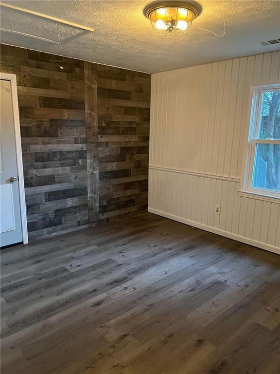 Unfurnished room featuring wood walls, a textured 