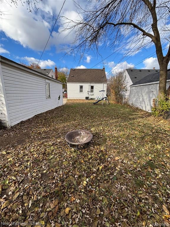 Rear view of property with a fire pit and an outbuilding