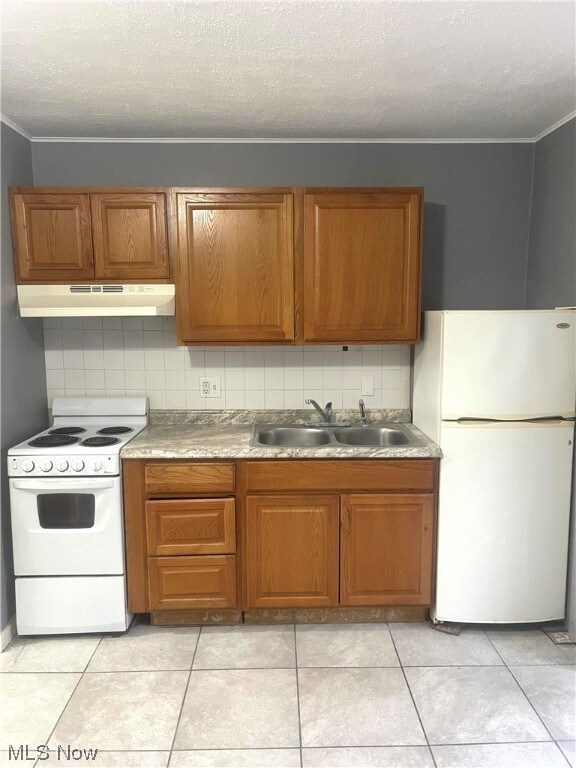 Kitchen featuring light tile flooring, tasteful backsplash, and white appliances