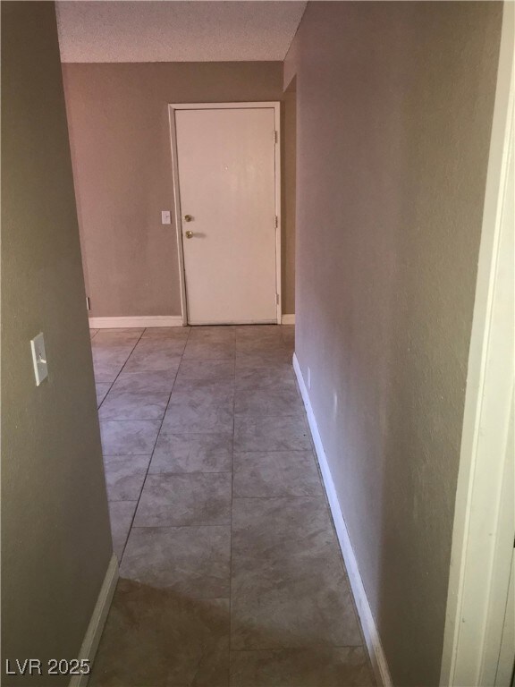 Hallway featuring baseboards and a textured ceilin