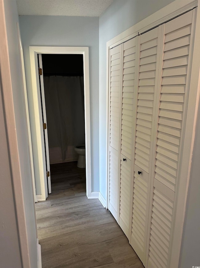 Hallway featuring light wood-style flooring and a textured ceiling