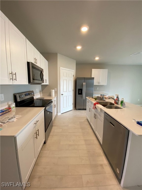 Kitchen with sink, white cabinetry, light hardwood