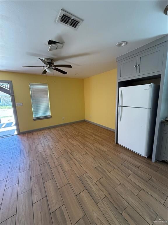 Unfurnished living room with a ceiling fan, light wood finished floors, and baseboards