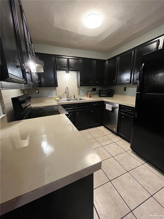 Kitchen featuring dark cabinetry, black appliances, a sink, light tile patterned floors, and light countertops