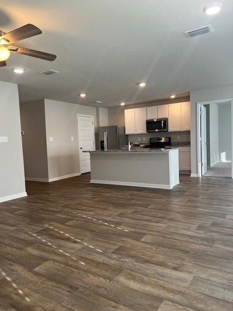 Kitchen with open floor plan, refrigerator, a center island with sink, recessed lighting, and dark wood finished floors