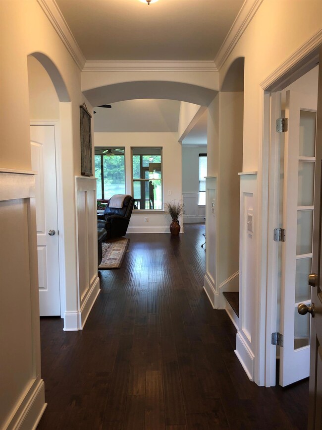 The Foyer area as you walk in. Nice architectural archways and outside rounded drywall corners, thick baseboard molding and wood farmhouse wanescoating.
