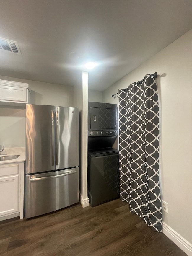 Kitchen with freestanding refrigerator, dark wood-style floors, white cabinets, and light countertops