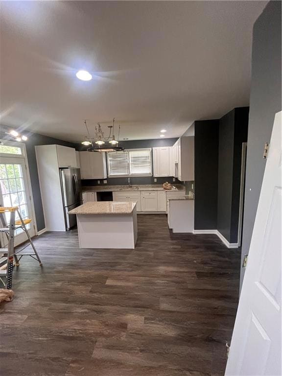 Kitchen with a center island, white cabinetry, dark wood-style flooring, refrigerator, and recessed lighting