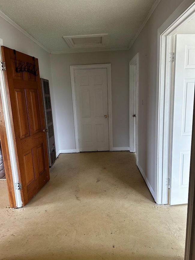 Hall with a textured ceiling and crown molding