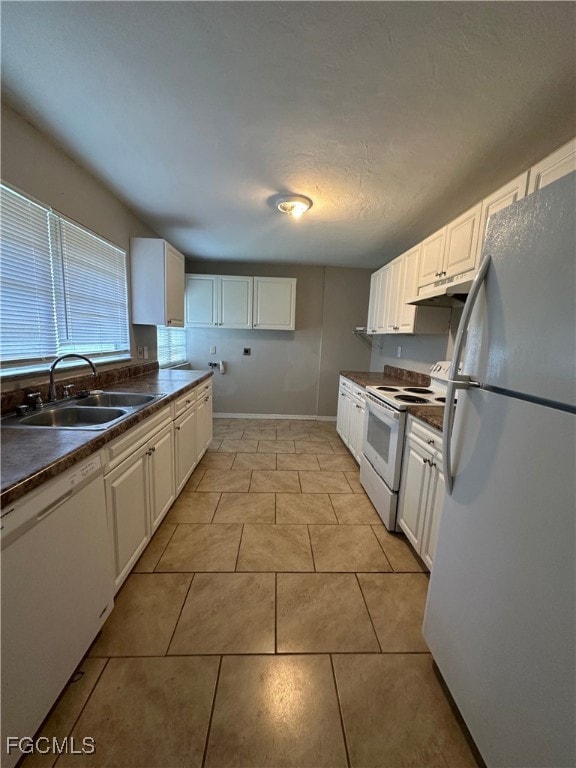 Kitchen featuring dark countertops, white appliances, white cabinets, and under cabinet range hood