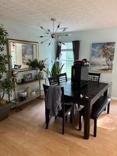 Dining room featuring a chandelier, light wood finished floors, and a textured ceiling