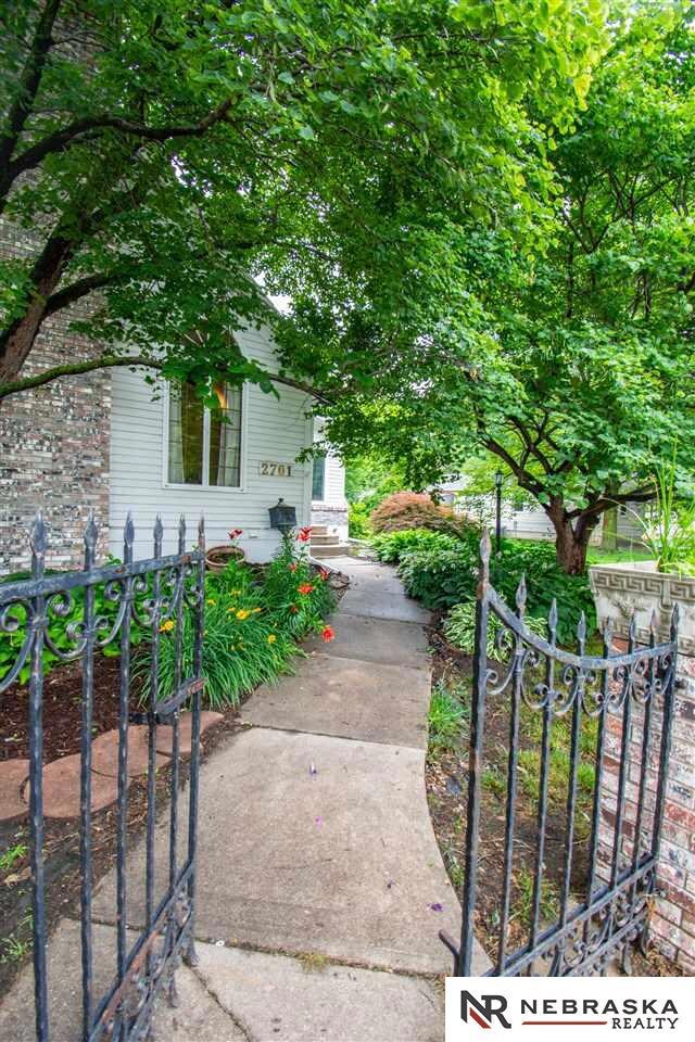 Beautiful iron gate opens to a fully fenced  yard.  Full of perennials and ferns. Mature trees and beautiful lawn spaces make this a magical setting for any home.
