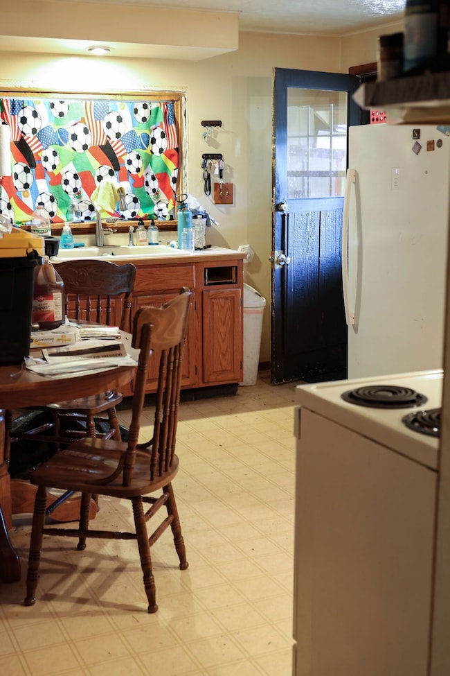 Kitchen with white appliances, light countertops, light flooring, and brown cabinetry