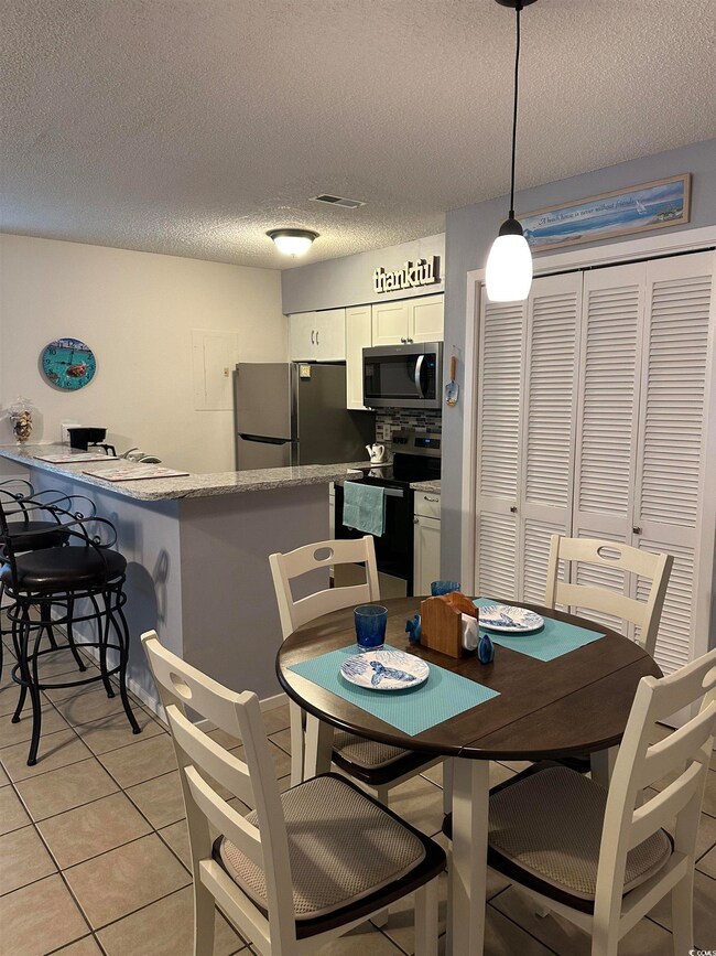 Tiled dining space featuring a textured ceiling