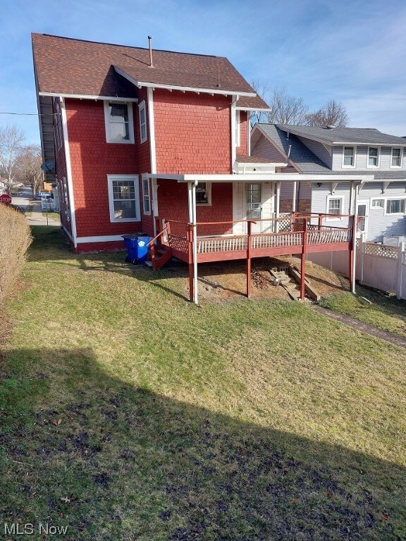 Rear view of house featuring a lawn and a deck
