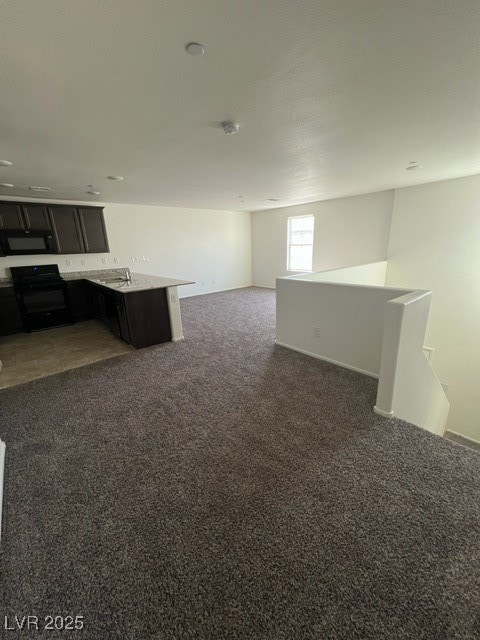 Kitchen with dark colored carpet, stove, open floor plan, a peninsula, and light stone counters