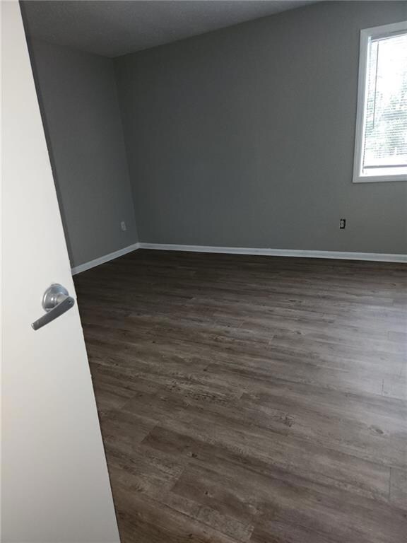 Unfurnished room with baseboards and dark wood fin