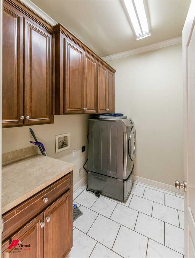 Laundry area featuring cabinet space, crown molding, washer hookup, and light marble finish flooring