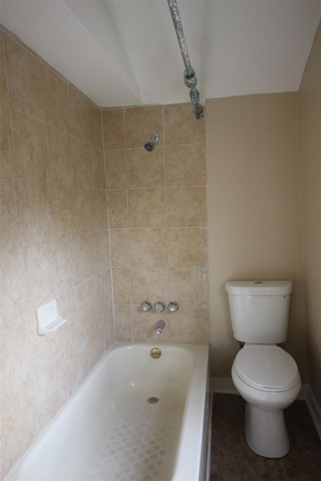 Bathroom with toilet, baseboards, and shower / ba