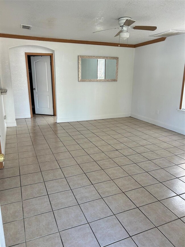 Spare room with light tile patterned floors, a textured ceiling, ceiling fan, and ornamental molding