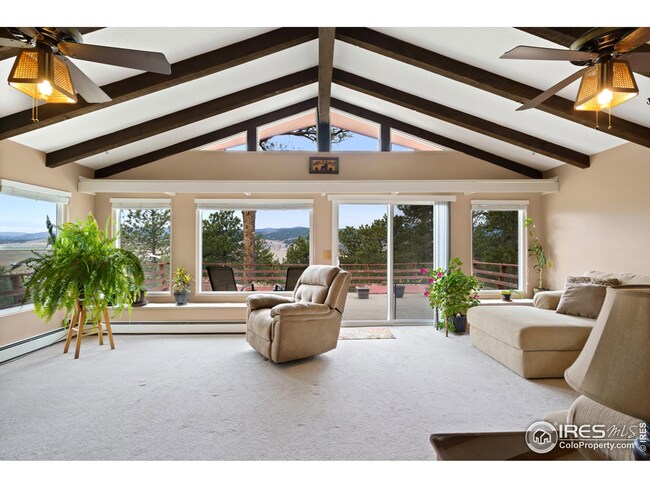 Enjoy the great room with wooden beams on the vaulted ceiling, a wall of windows, and double ceiling fans.