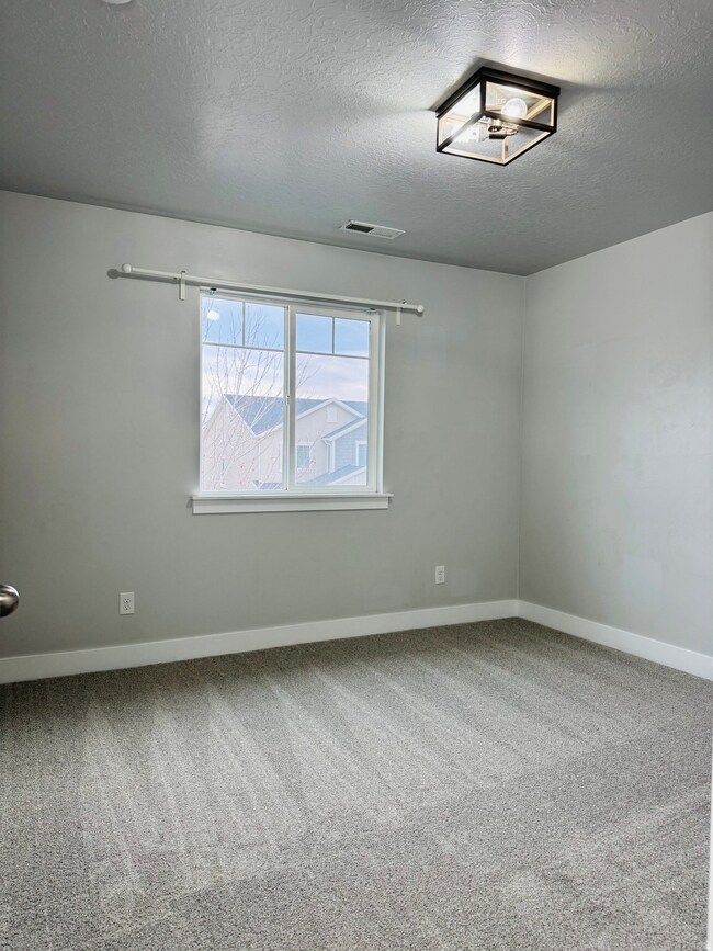 Empty room featuring light colored carpet and a textured ceiling