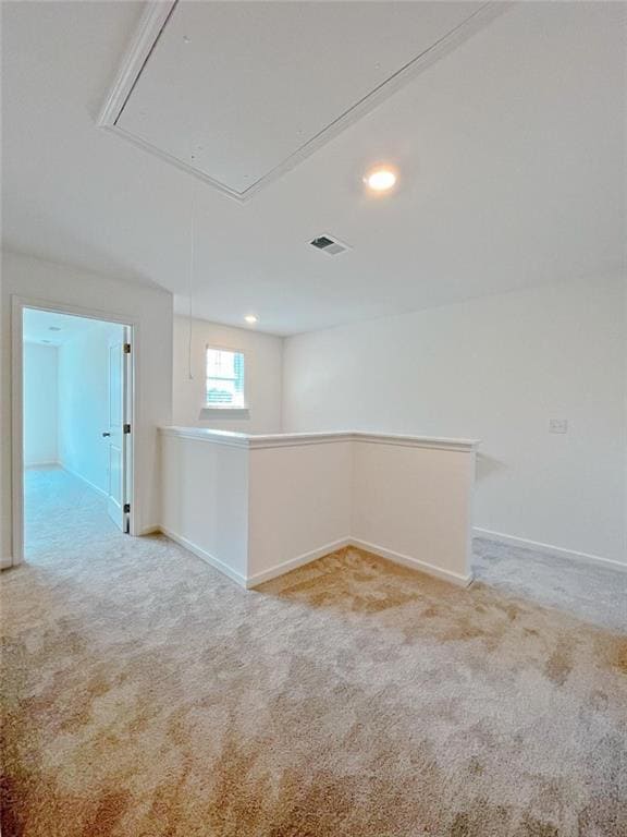 Carpeted empty room featuring attic access, baseboards, and recessed lighting