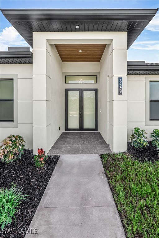 Property entrance featuring stucco siding, french