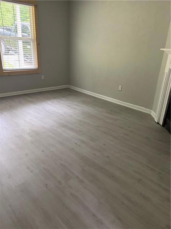 Unfurnished room featuring dark wood-type flooring and baseboards