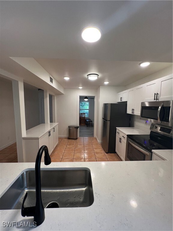 Kitchen with light tile patterned floors, fridge,