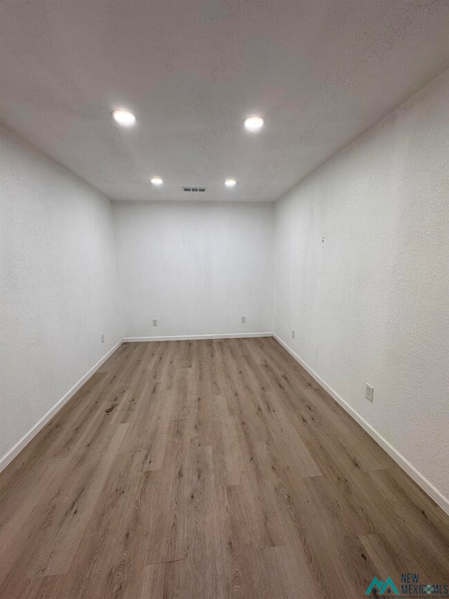 Empty room with wood finished floors, recessed lighting, a textured ceiling, and a textured wall