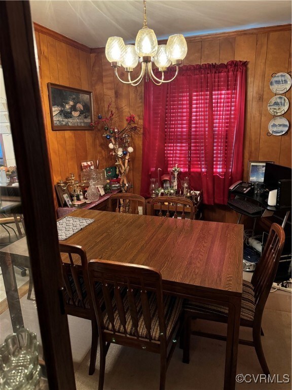 Dining room featuring wood walls and a chandelier