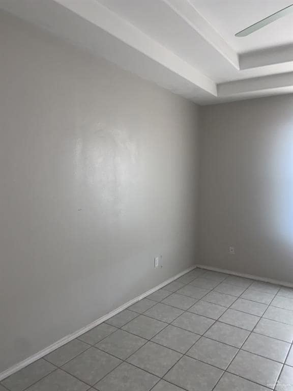 Spare room with light tile patterned flooring, baseboards, and a raised ceiling