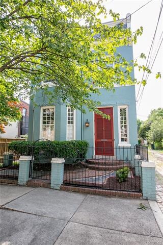 The brick and slate front courtyard is surrounded by an iron fence and gate.