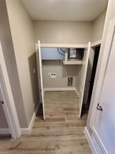 Clothes washing area featuring electric dryer hookup, baseboards, wood finished floors, and laundry area