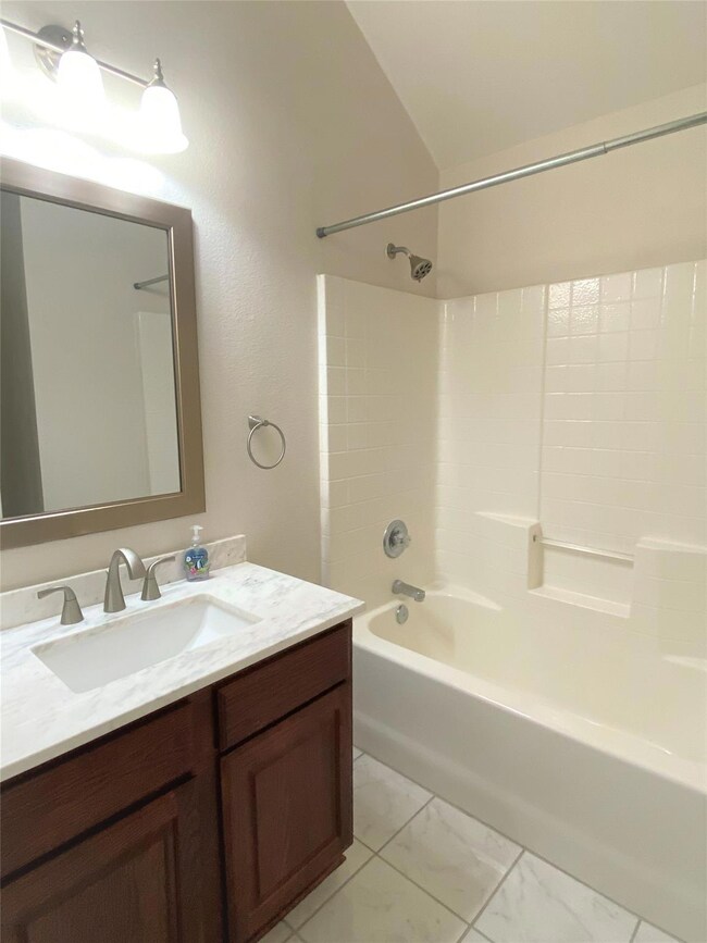 Bathroom featuring shower / washtub combination, vanity, lofted ceiling, and tile patterned flooring