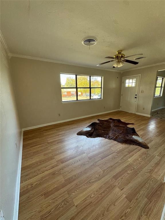 Entry with ornamental molding, light wood-type flooring, a textured ceiling, and ceiling fan