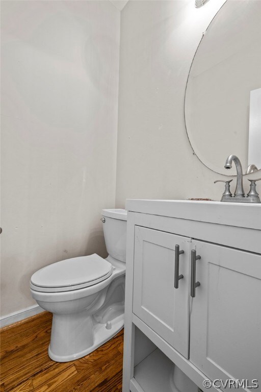 Powder room featuring hardwood flooring, toilet, a