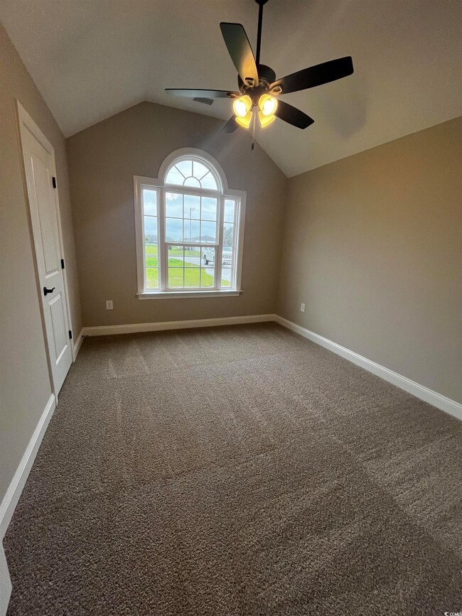 Carpeted spare room featuring vaulted ceiling, cei