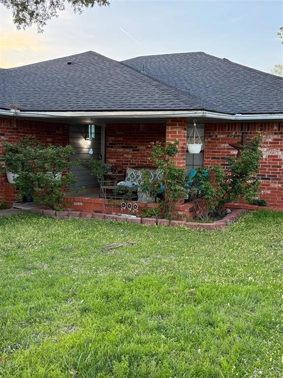 Rear view of property featuring a yard, a shingled