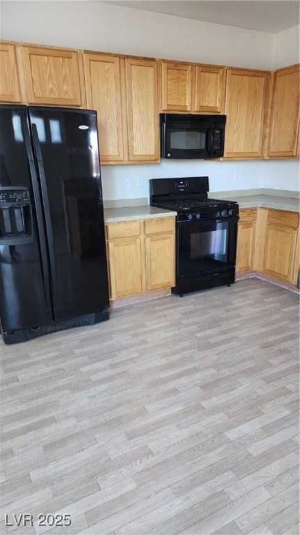 Kitchen with fridge, stove, light wood-type floori