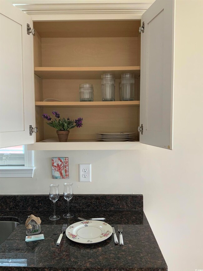 Detailed view of dark stone countertops, open shelves, and white cabinets
