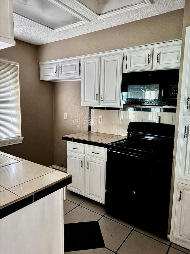 Kitchen with black range with electric stovetop, b