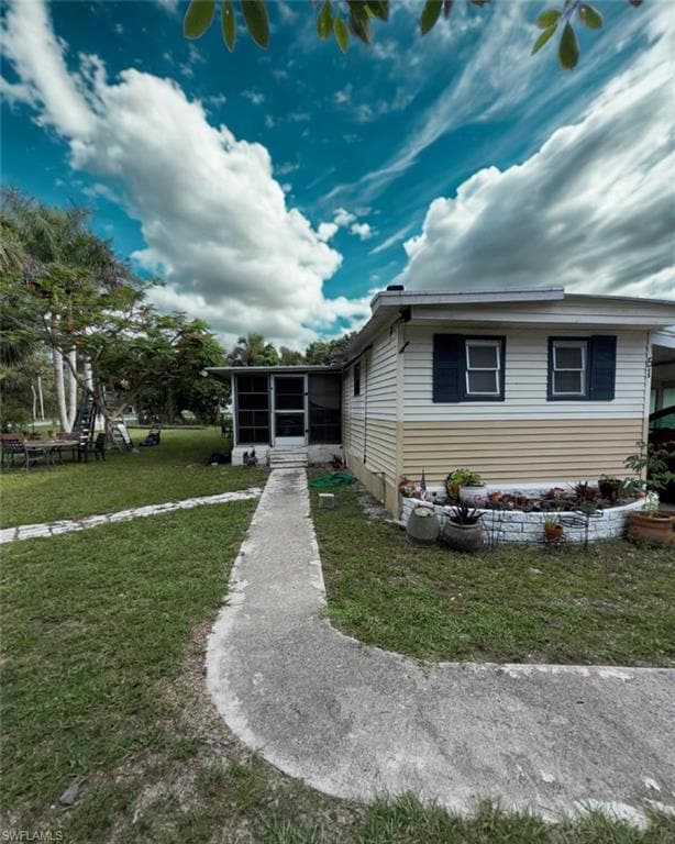 View of front facade featuring a sunroom and a front yard