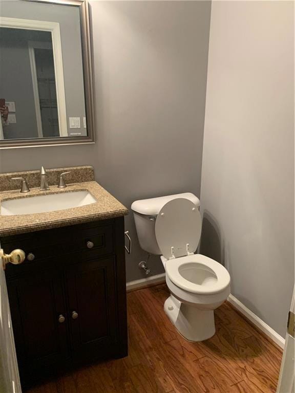 Half bathroom featuring wood finished floors and vanity
